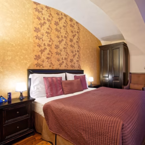 Single Rooms Single room with plum-colored bedspread, nightstand lamps, and dark wood wardrobe at Skaritz Hotel Bratislava.
