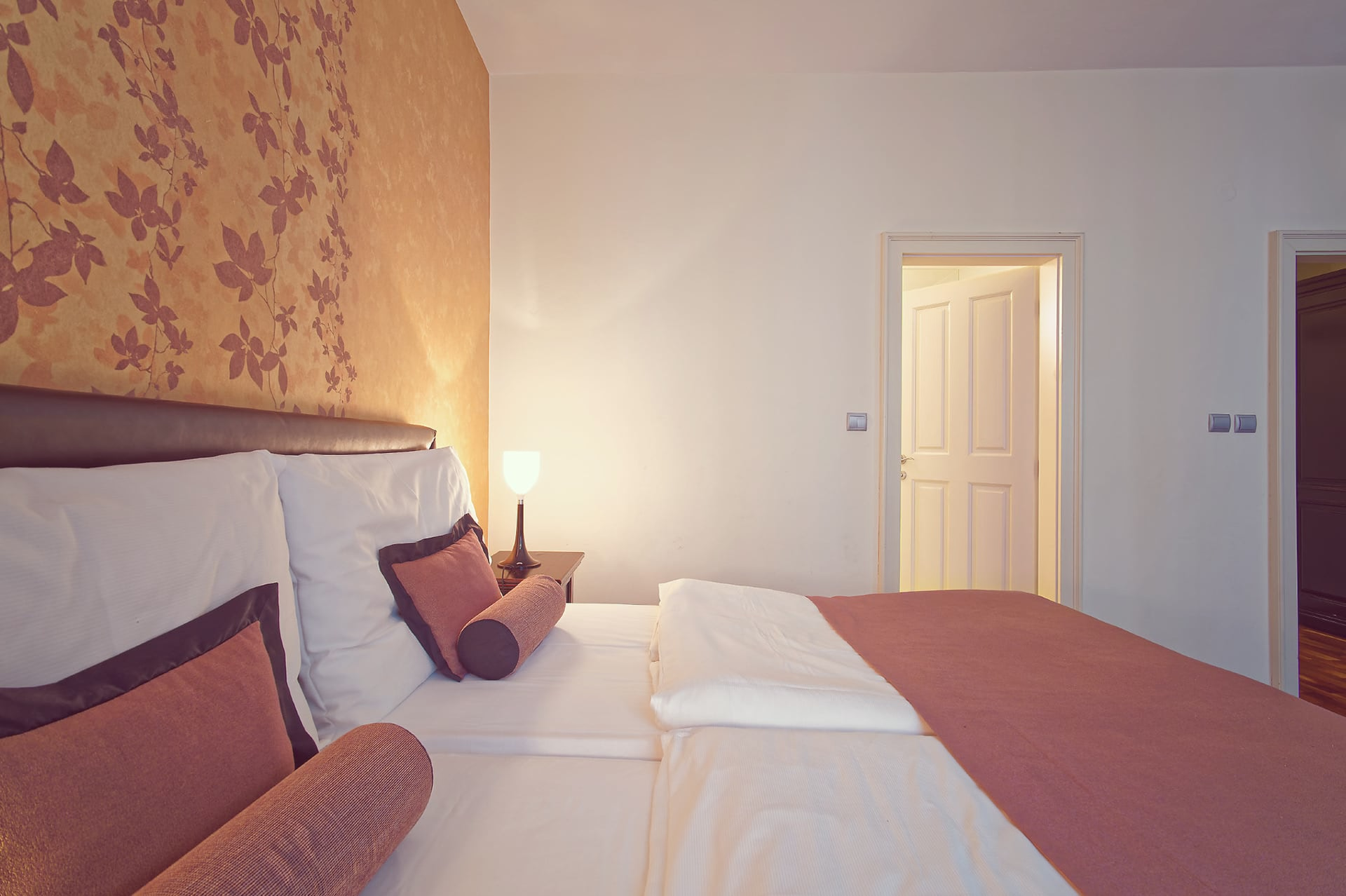 Close-up view of double bed pillows and bolster cushions looking towards the entry door.