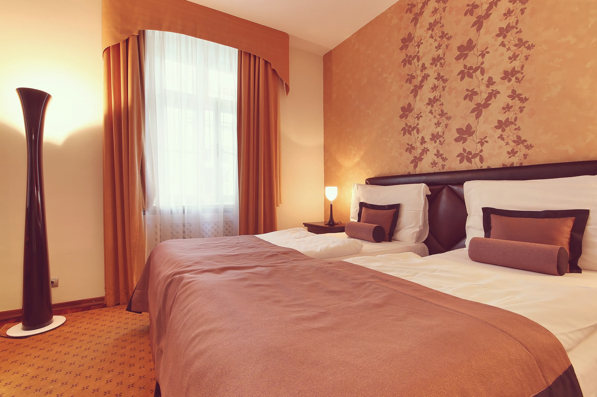 Double bed with bedside lamp, floor lamp, and curtained window at Skaritz Hotel Bratislava.