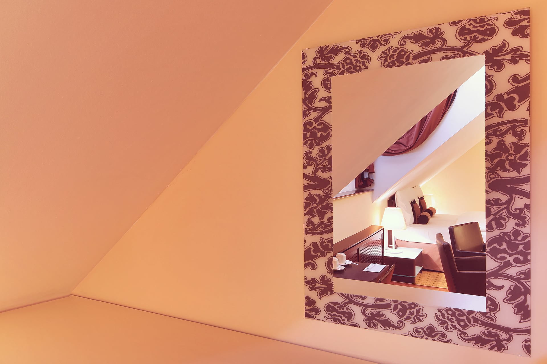 Decorative wall mirror reflecting a cozy attic double room setting at Skaritz Hotel.