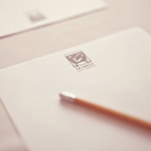 Close-up view of elegant Skaritz Hotel & Residence stationery paper with logo and a wooden pencil, representing business travel services.