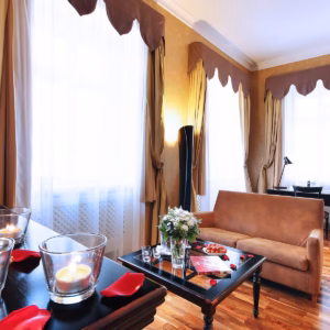 Romantic weekend package setup in a hotel suite featuring lit candles, rose petals, fresh flowers, and fresh strawberries on a table
