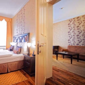 Suites & Apartments Skaritz Hotel luxury suite and apartment featuring a spacious bedroom with king bed and living room through door.