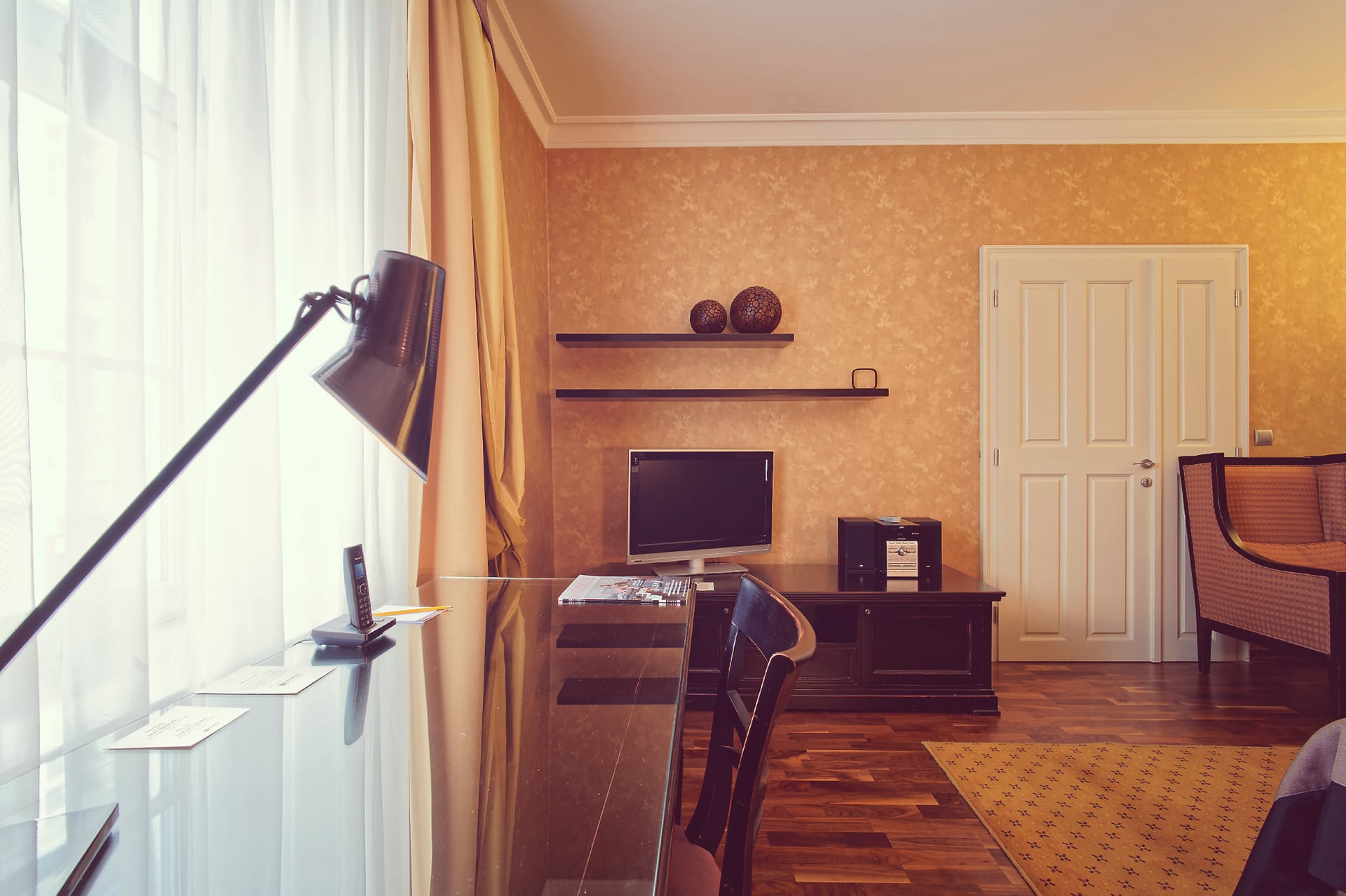 Work desk next to window with TV and seating in the background at SKARITZ Hotel